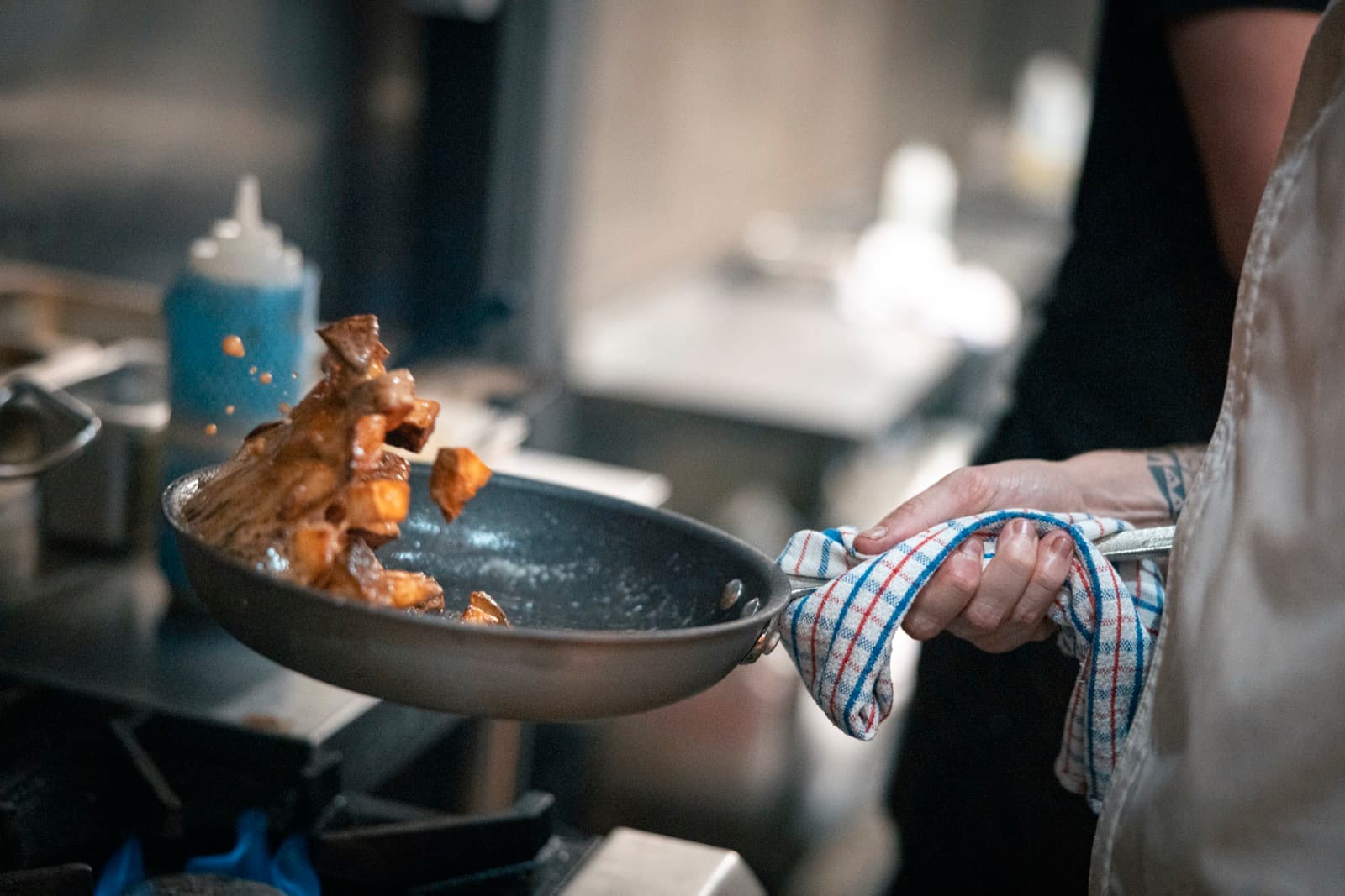 Pan flipping confit ingredients at Shelly