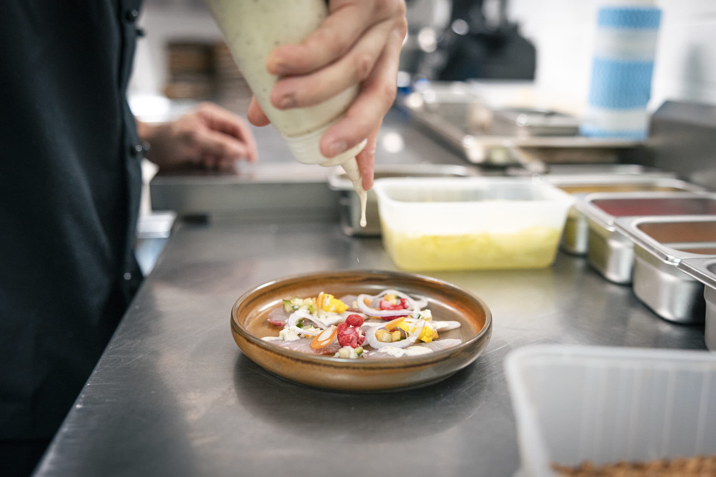 Chef pouring sauce over a kingfish ceviche course at Shelly